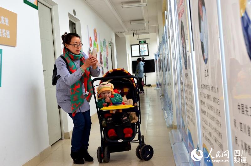 一位母亲带着年幼的孩子，在家庭教育基地学习后，对宣传画板进行拍照。.jpg